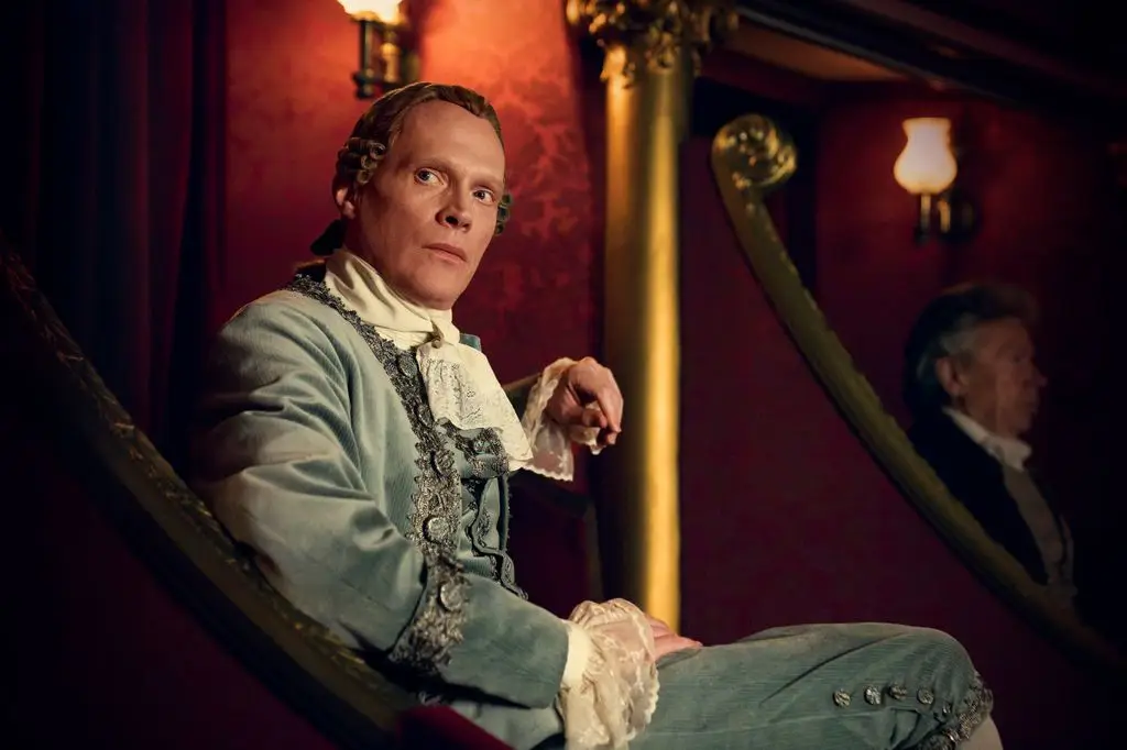 man in period clothing sitting in a theater seat