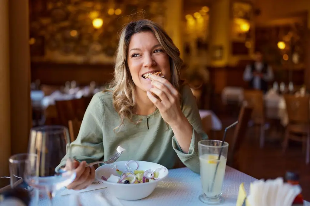 Good day woman dreaming while having salad for lunch in a restaurant.