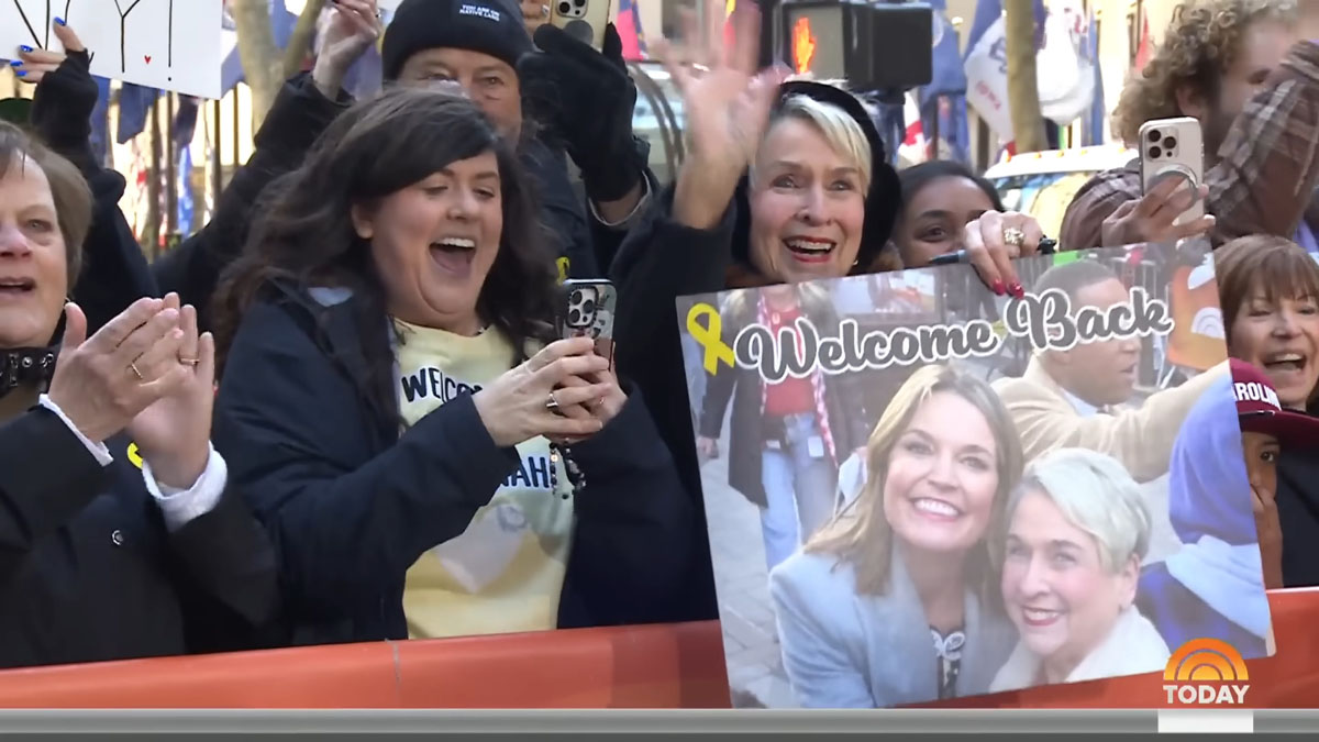 A woman in the crowd outside today holds a welcome sign with a photo of her and Savannah and a yellow ribbon on it.