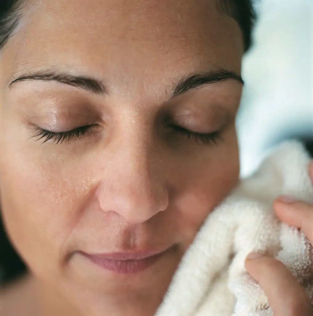 woman holding a washcloth to face