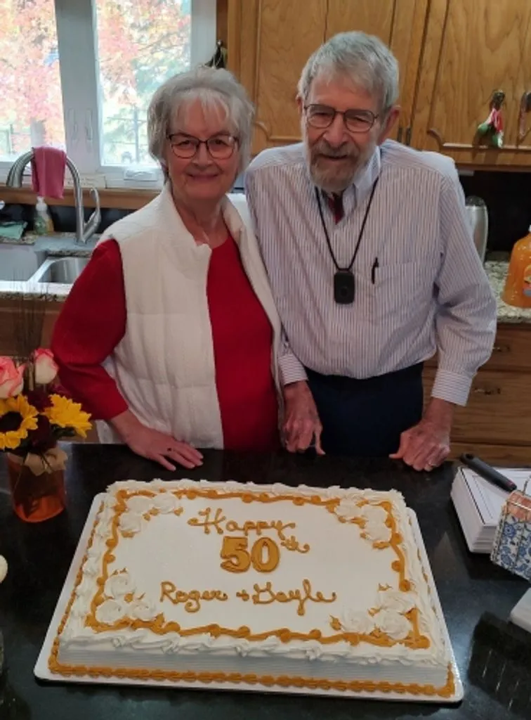 Gayle R Wilson and a man standing behind a "Happy 50th Roger and Gayle" cake.
