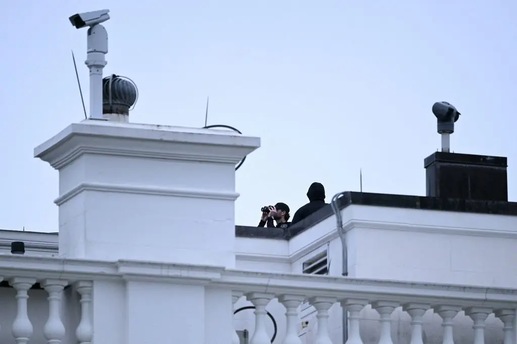 White Home capturing suspect recognized 2 A police officer uses binoculars on the roof of a White House building