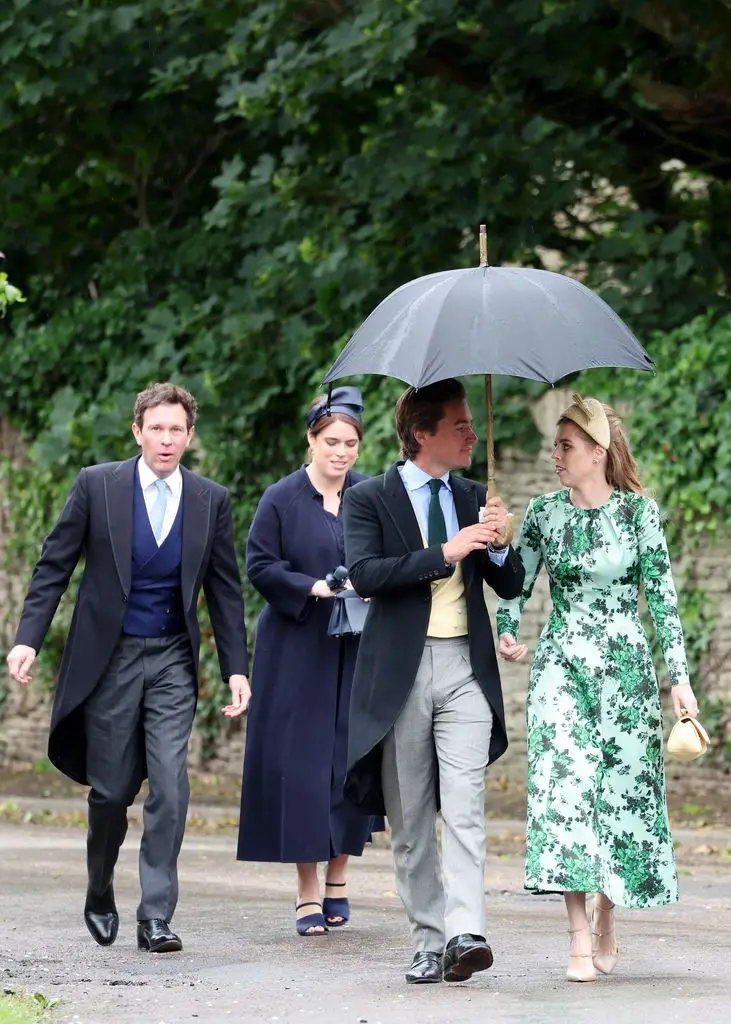 Peter Phillips and Harriet Sperling share their first romantic kiss after a fairytale marriage ceremony 11 Four people walking on a path, one holding an umbrella. No celebrities detected.