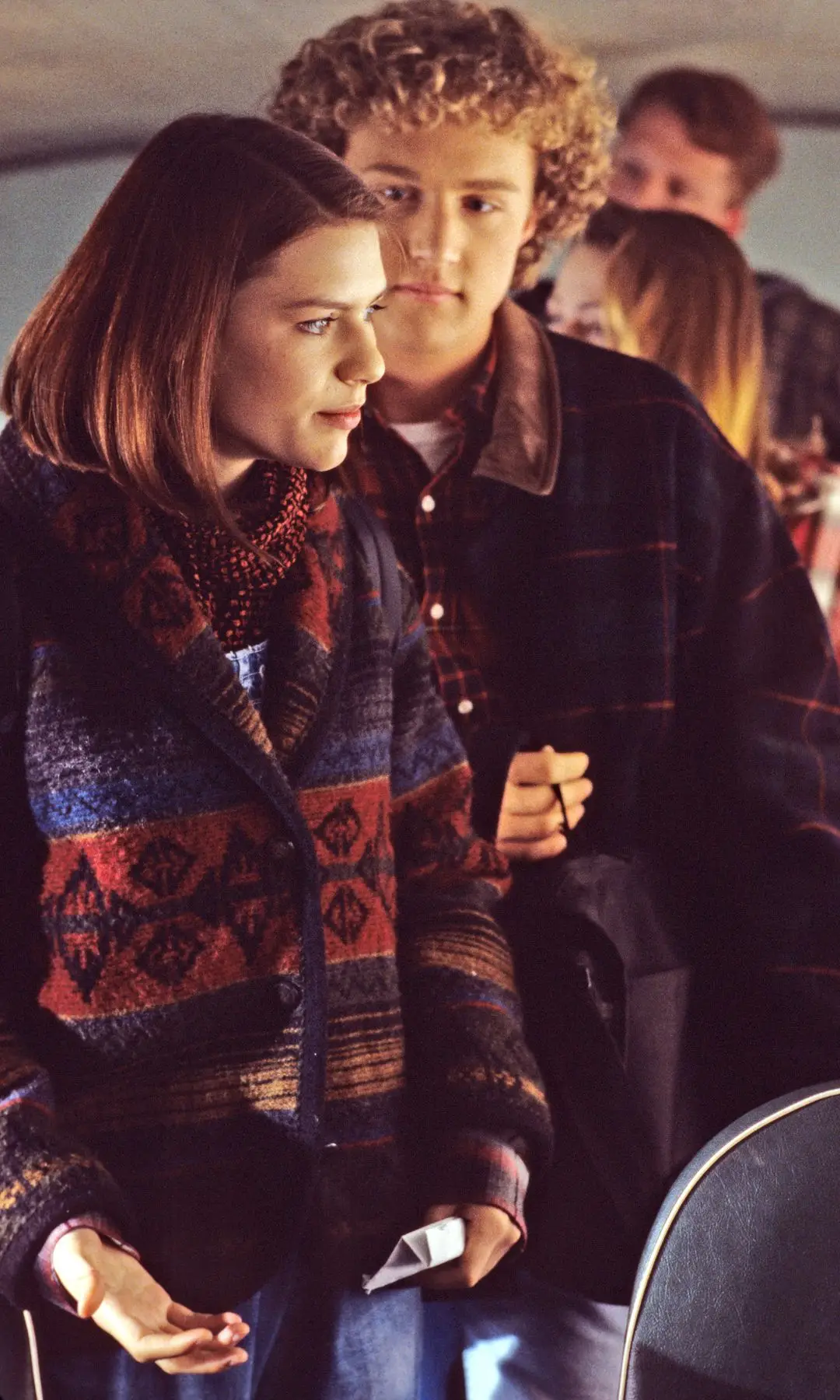 Claire Danes stands next to a curly-haired man, both looking ahead on a bus.