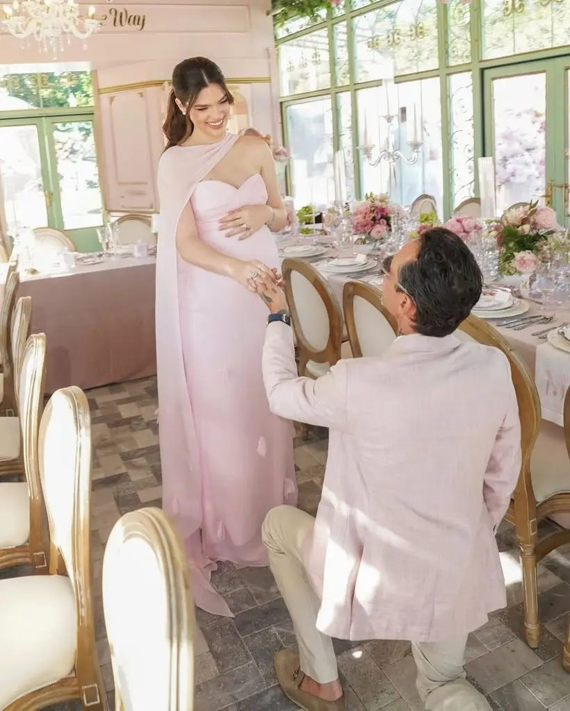 Marc Anthony's spouse Nadia Ferreira reveals off her child bump in lavish pink celebration forward of daughter's arrival 1 Marc kneels in front of Nadia, creating a romantic and intimate scene