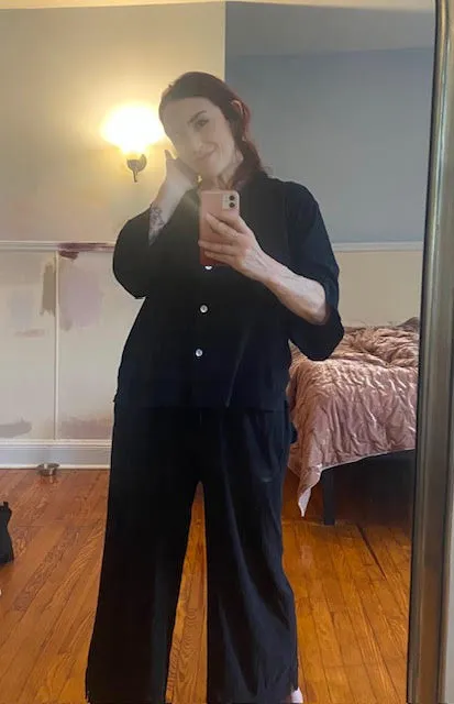 A woman in black outfit taking a mirror selfie.