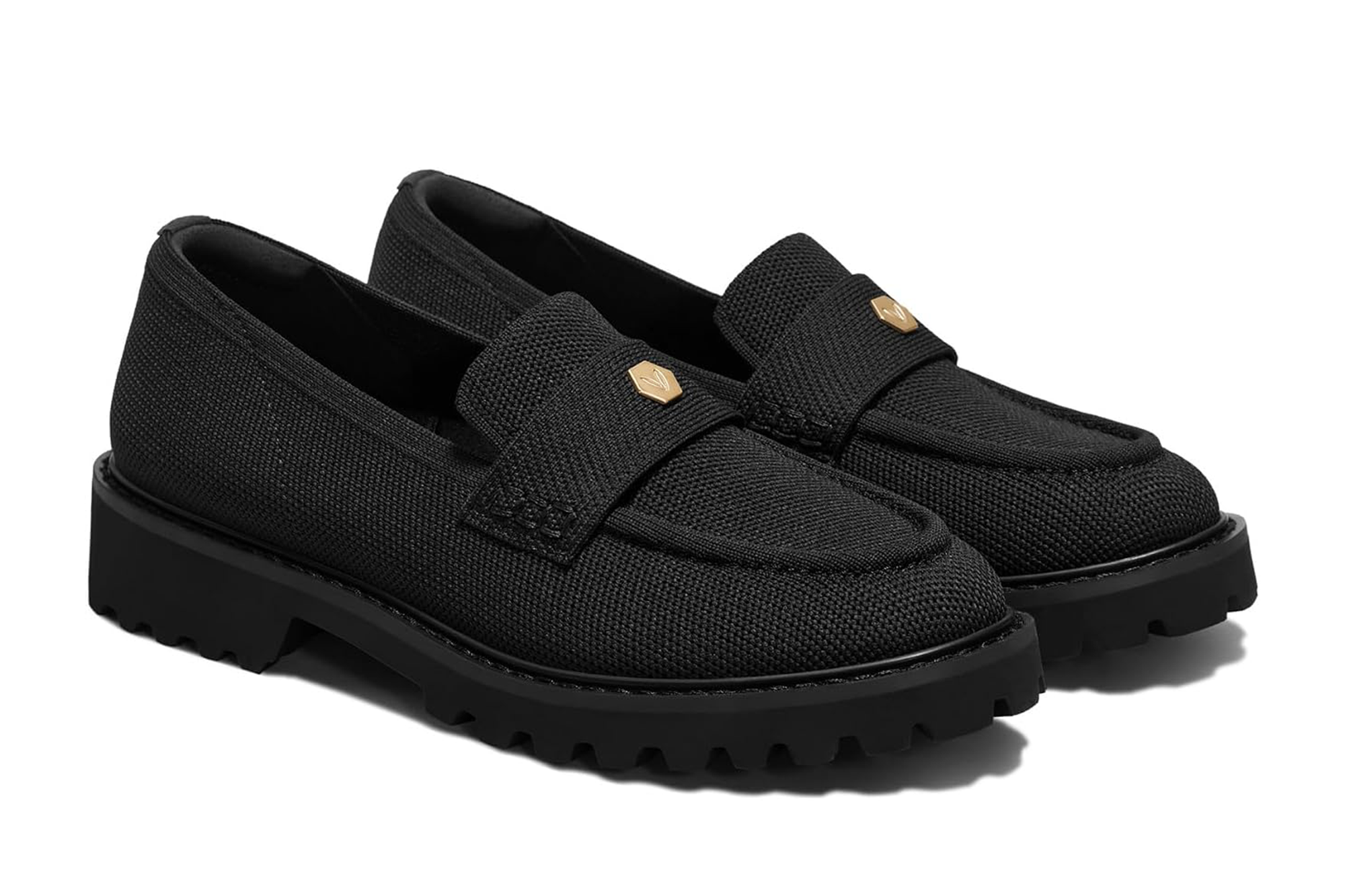 A pair of black woven loafers with gold details on the straps and thick lug soles.