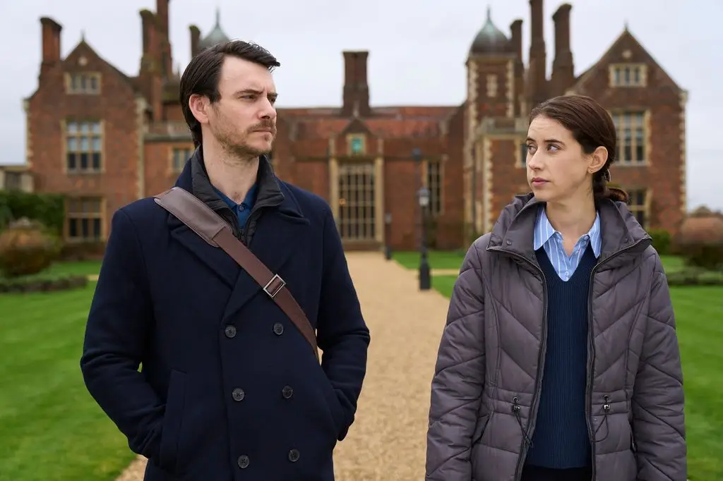 Man and woman looking at each other, standing in front of a country mansion