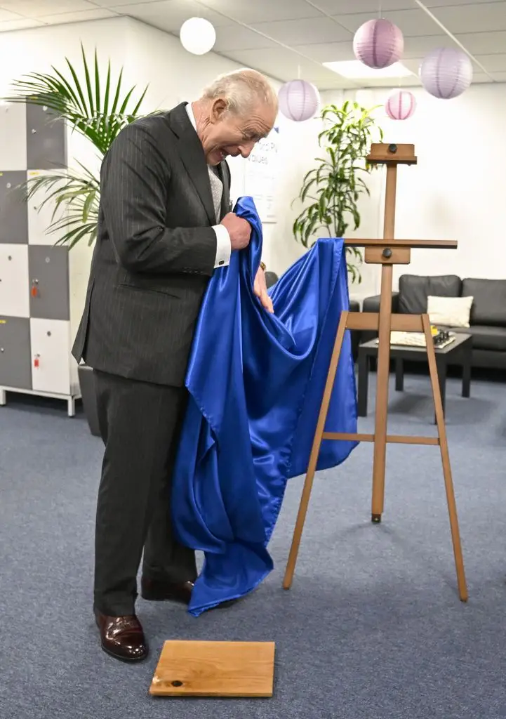 Britain's King Charles III reacts by unveiling a plaque that accidentally falls to the ground during a visit to Oxford Photovoltaics, a company developing advanced solar panels, in Kidlington, Oxfordshire, west of London, March 27, 2026.