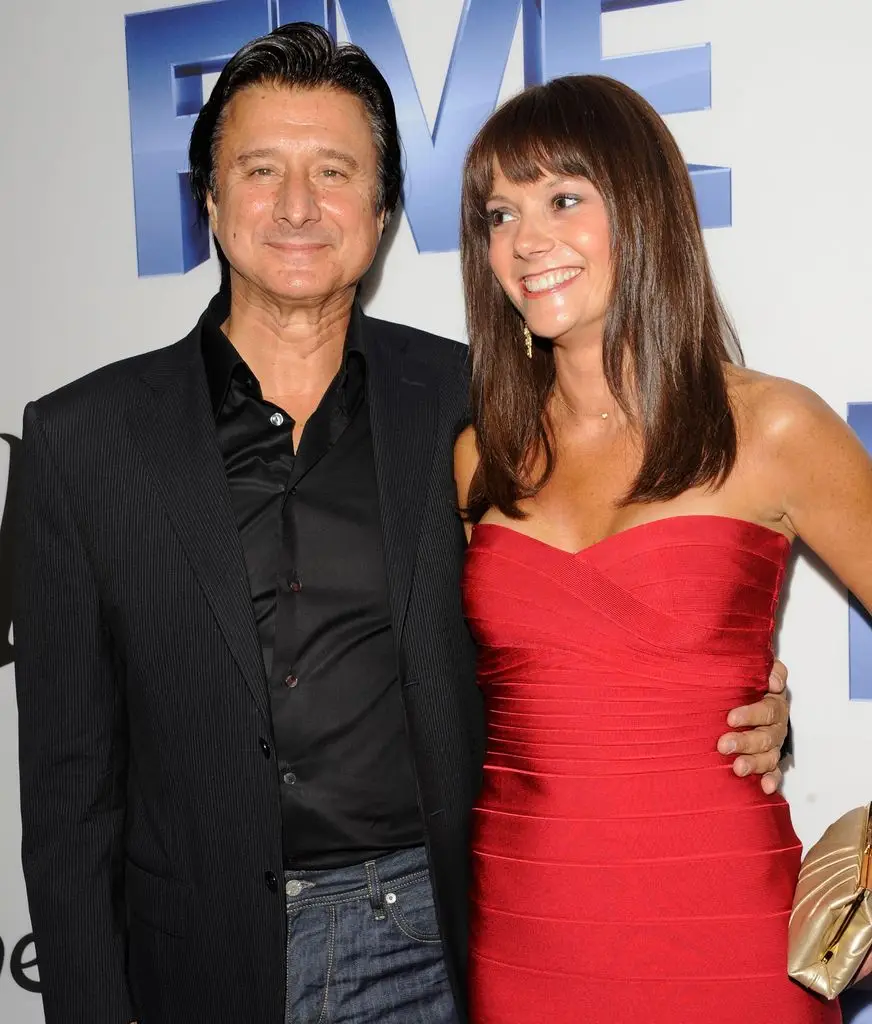 What occurred to Do not Cease Believin' singer Steve Perry? In his solitary life, removed from the highlight 4 Steve Perry and a woman in a red dress pose for a photo, smiling.