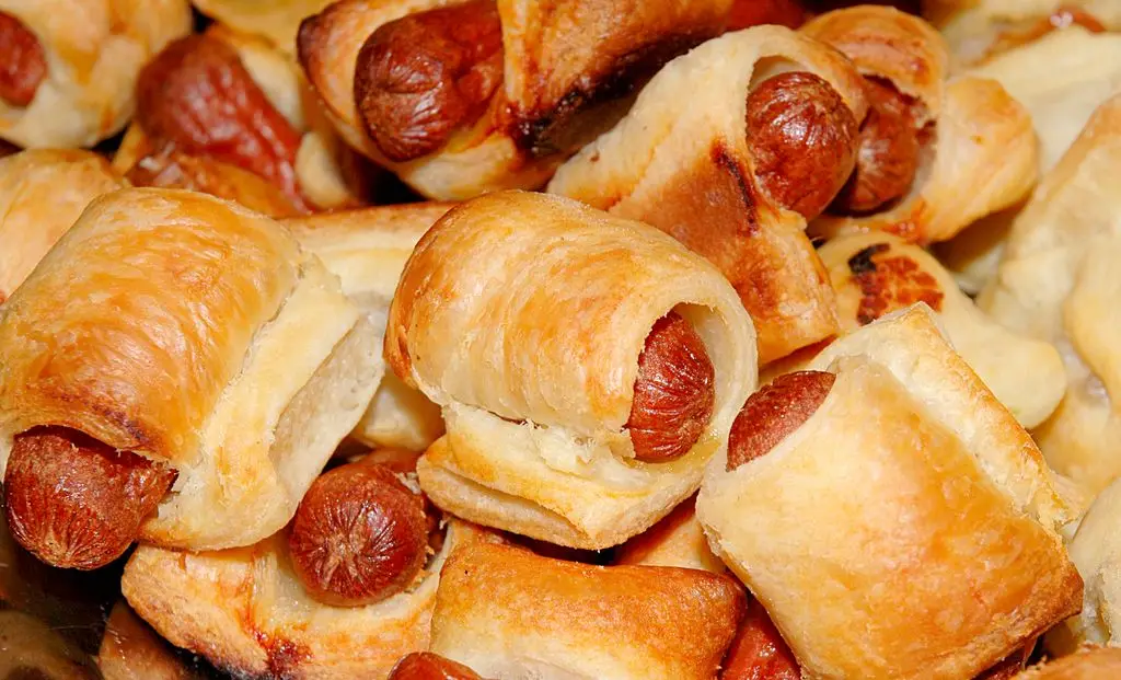 A tray filled with pigs in blankets, golden pastries wrapped around little sausages.