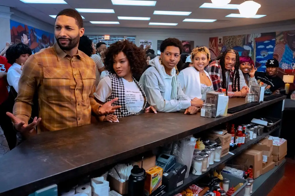 Group of people at a counter with condiments and boxes, smiling and posing.