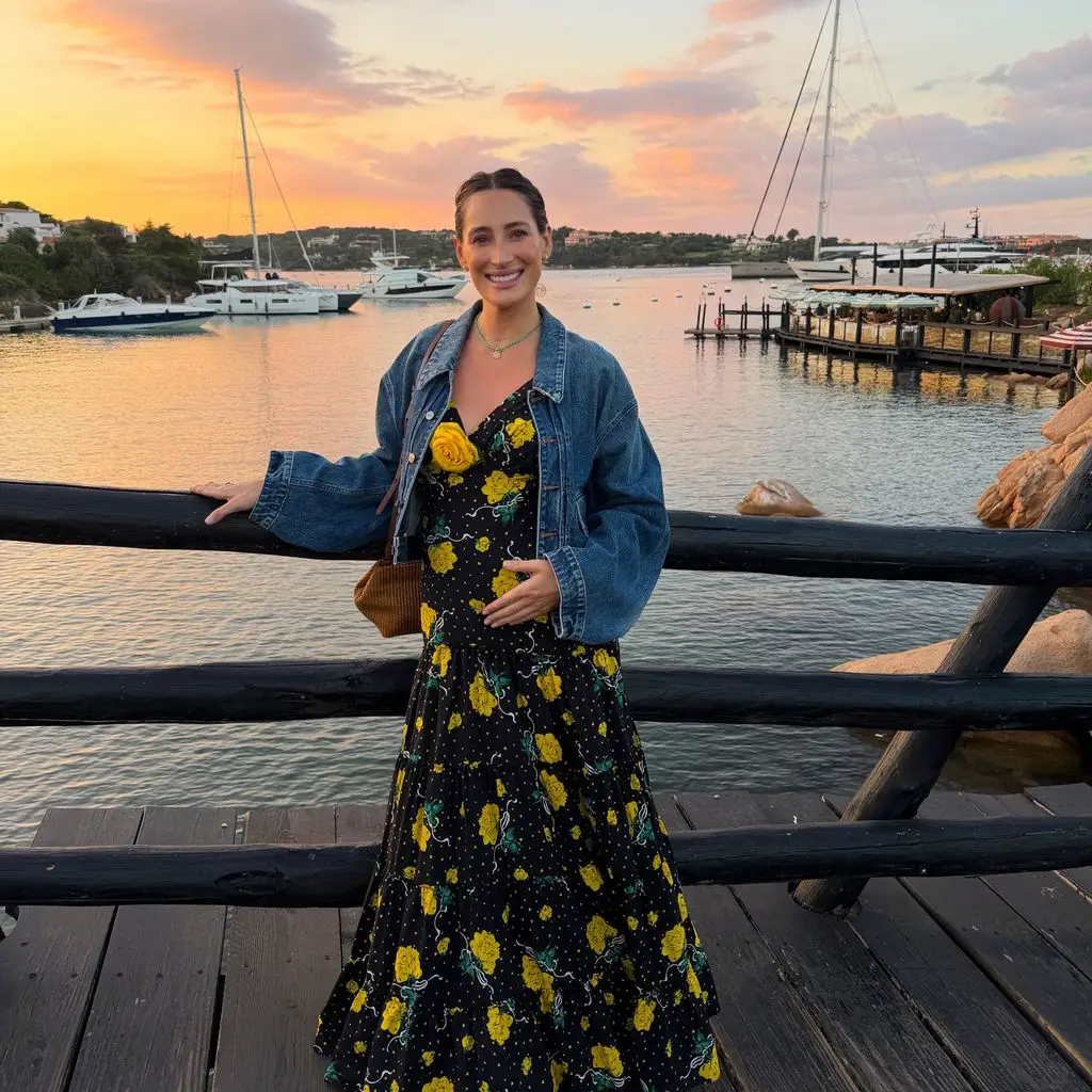 Jessica Springsteen cradles her baby bump in a black and yellow dress near a pier, shared on Instagram